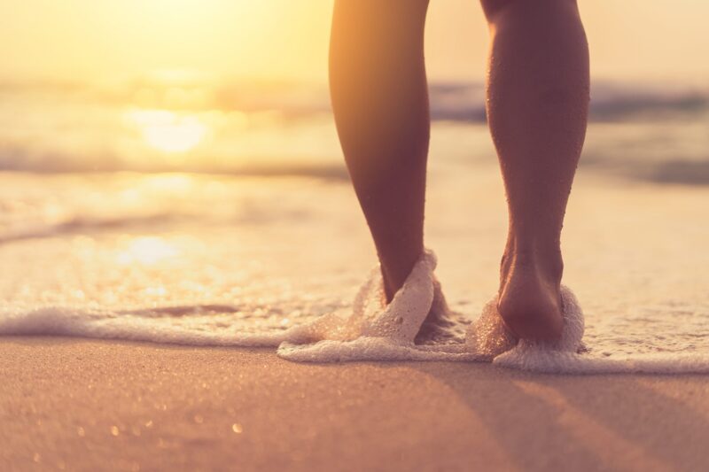 woman putting her feet in water at the beach
